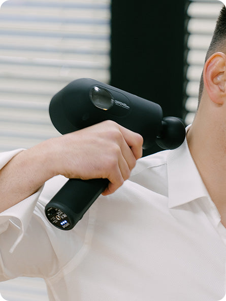 A young man using the opove Apex Massage Gun—a premium percussive therapy device with an ergonomic 45° grip—to relieve muscle tension in his shoulder