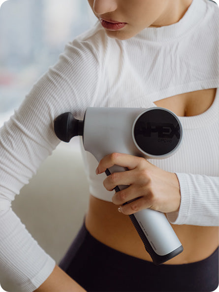 Young woman using the handheld opove Apex Massage Gun—a handheld premium percussive therapy device—to relieve muscle tension in her arm.