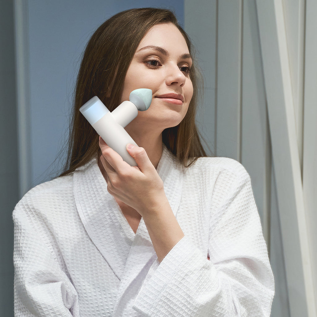 A woman gently massages her face with the Opove M3 Mini massage gun