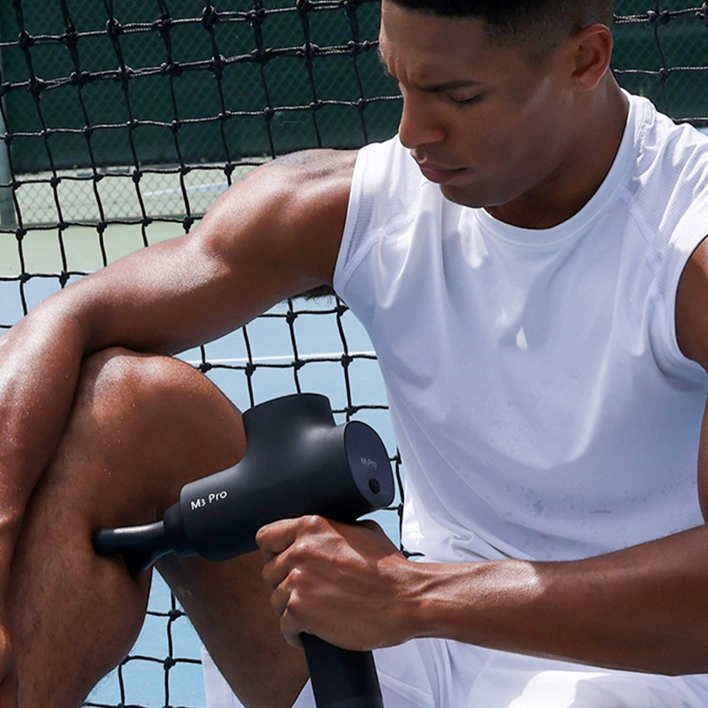 An athlete massages his calves with the opove M3 Pro massage gun after a tennis match.