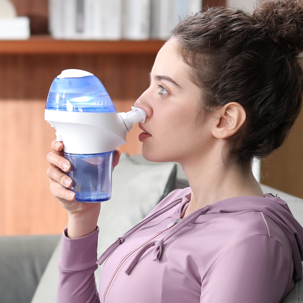 Young woman using opove Nascare nasal irrigator to clean nasal cavity